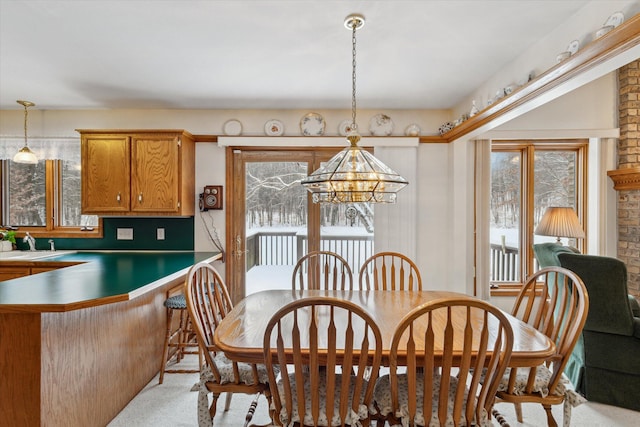 dining space featuring sink, a healthy amount of sunlight, and a notable chandelier