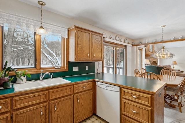 kitchen with white dishwasher, pendant lighting, kitchen peninsula, and sink