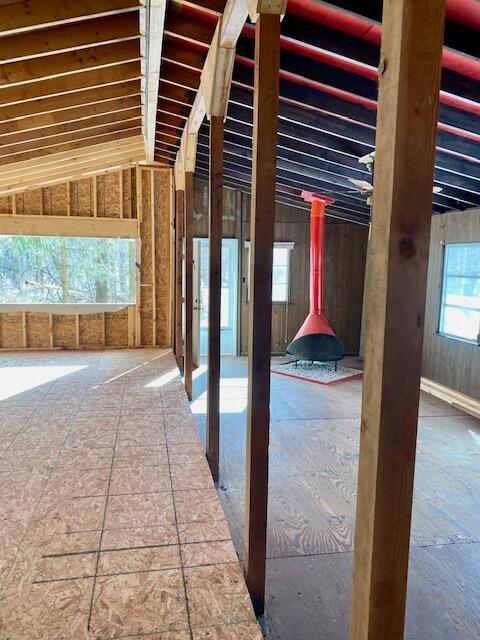 miscellaneous room featuring vaulted ceiling and a wood stove