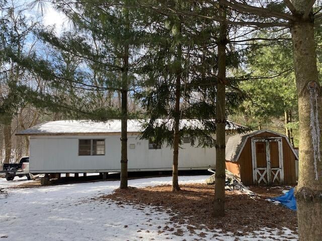 view of snowy exterior featuring a storage shed