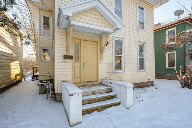 snow covered property entrance featuring central air condition unit