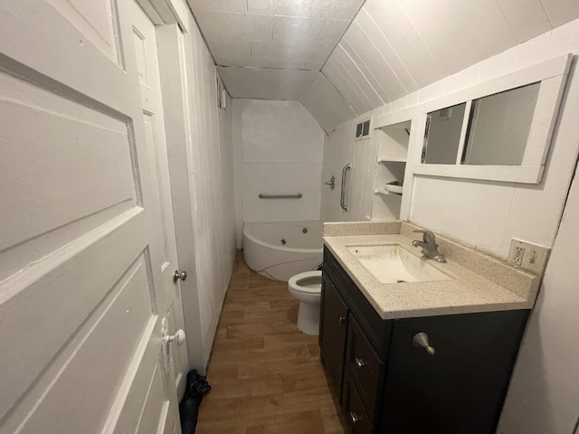 bathroom with hardwood / wood-style floors, vanity, lofted ceiling, toilet, and a tub to relax in