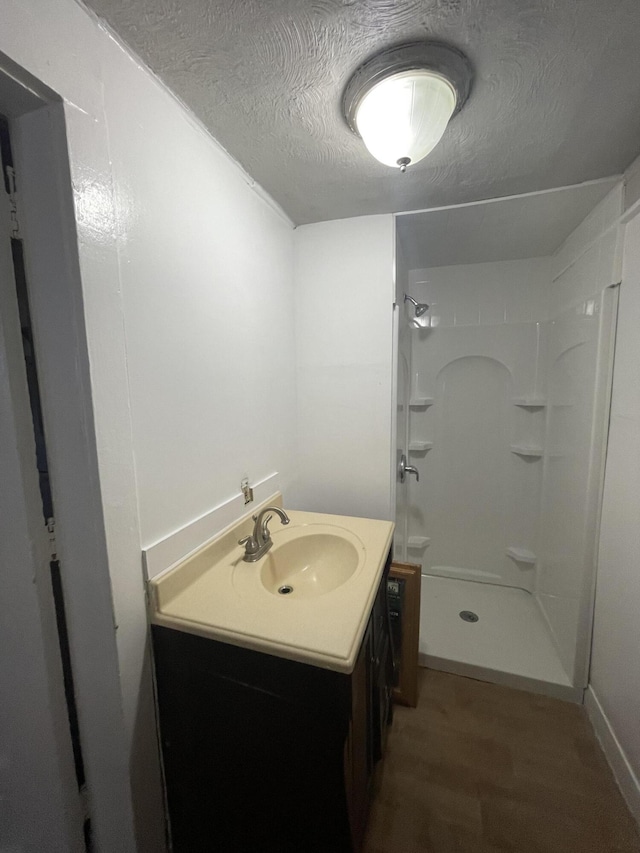 bathroom with hardwood / wood-style floors, vanity, and walk in shower