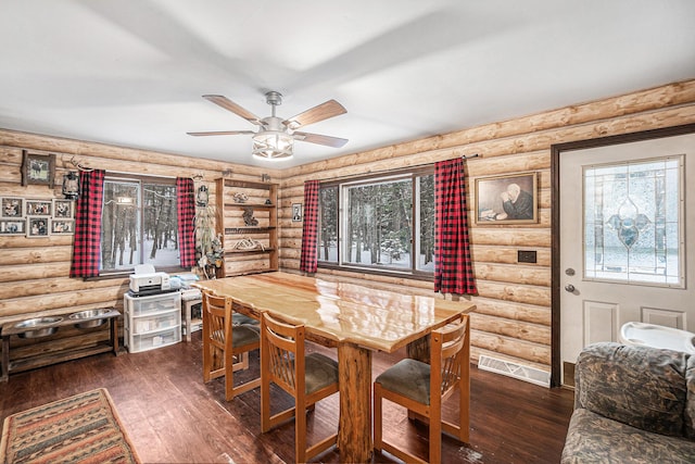 dining room with ceiling fan, log walls, and dark hardwood / wood-style floors