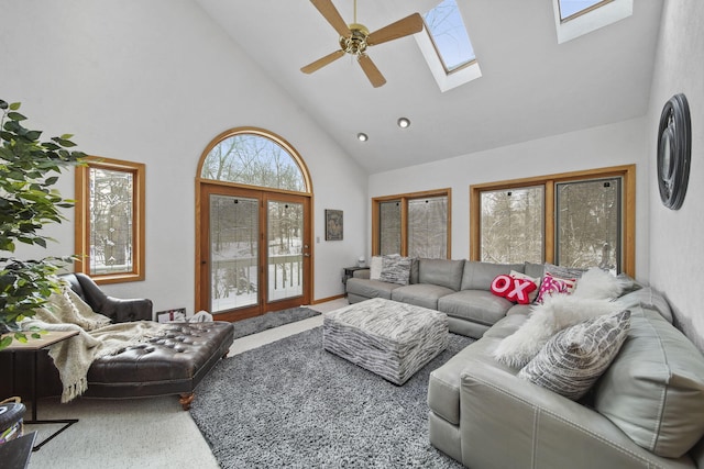 carpeted living room with a skylight, high vaulted ceiling, ceiling fan, and a healthy amount of sunlight