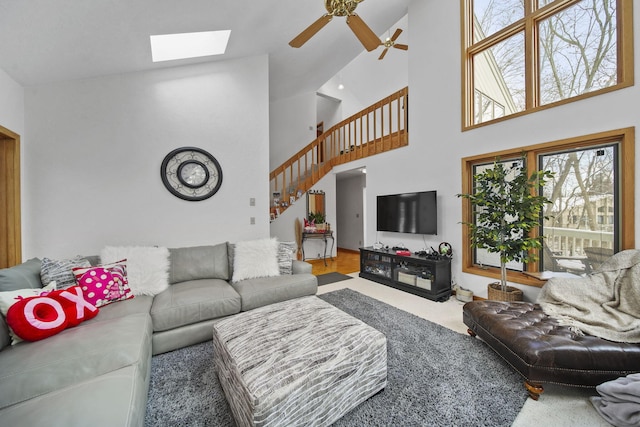 living room with ceiling fan, high vaulted ceiling, and a skylight