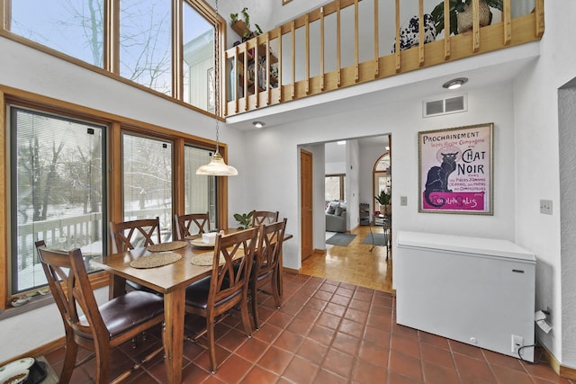 dining area featuring a towering ceiling and dark tile patterned flooring