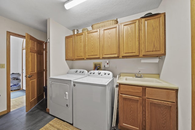 laundry area with sink, cabinets, dark hardwood / wood-style flooring, a textured ceiling, and washer and clothes dryer