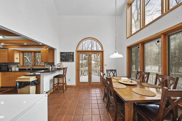 dining area with dark tile patterned floors, a towering ceiling, sink, and french doors