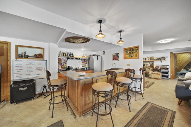 bar featuring stainless steel refrigerator, sink, light tile patterned floors, and hanging light fixtures