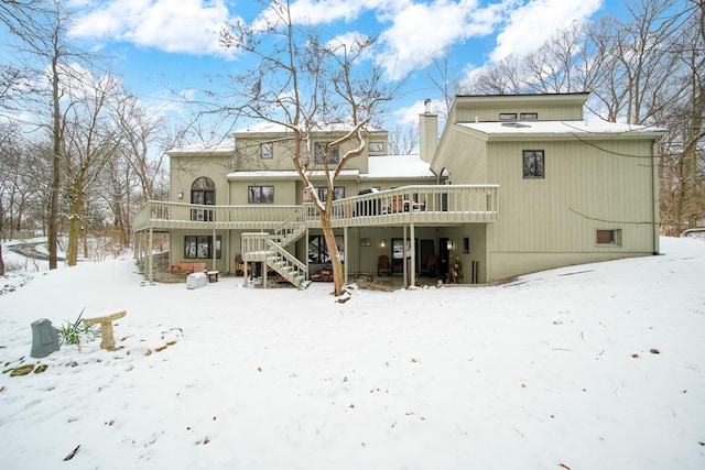 snow covered rear of property with a wooden deck