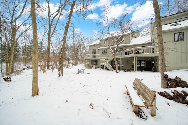 snow covered rear of property with a deck