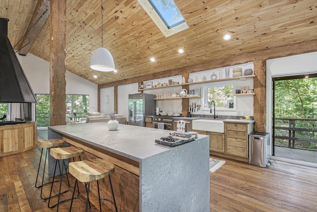 kitchen with pendant lighting, high vaulted ceiling, sink, stainless steel refrigerator with ice dispenser, and a skylight