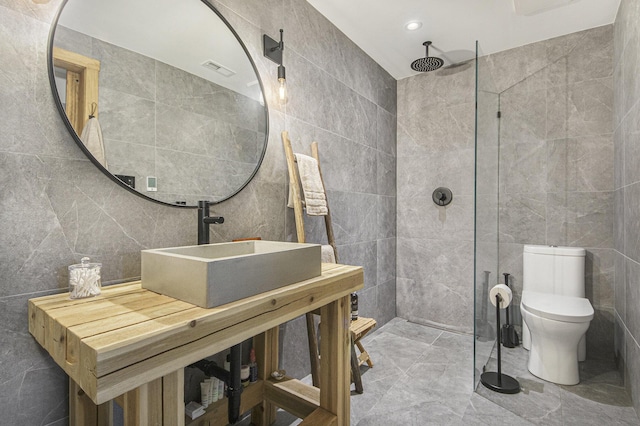 bathroom with walk in shower, vanity, toilet, and tile walls