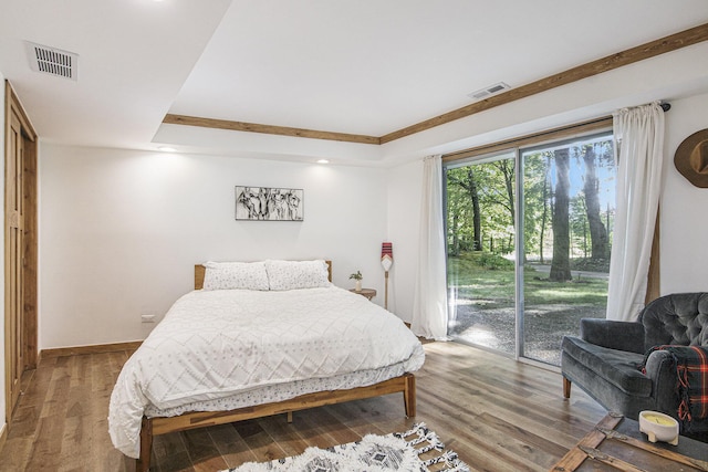 bedroom featuring hardwood / wood-style floors, access to outside, and a tray ceiling