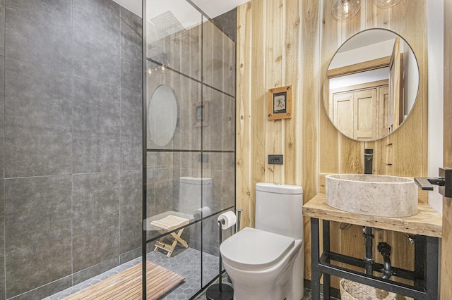 bathroom with a shower, toilet, wooden walls, and sink