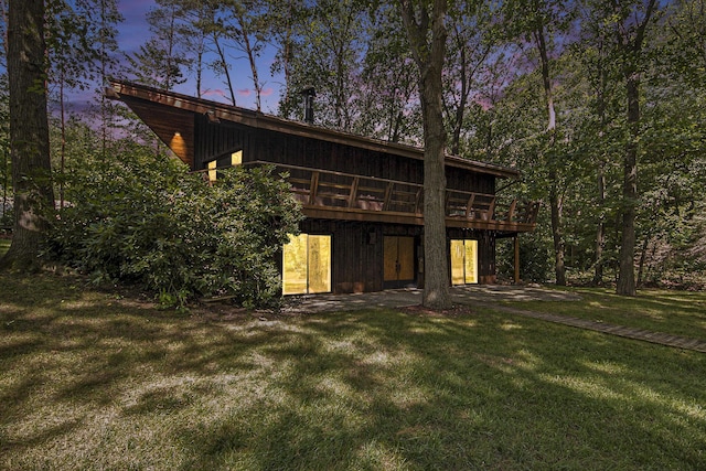 back house at dusk with a yard and a deck