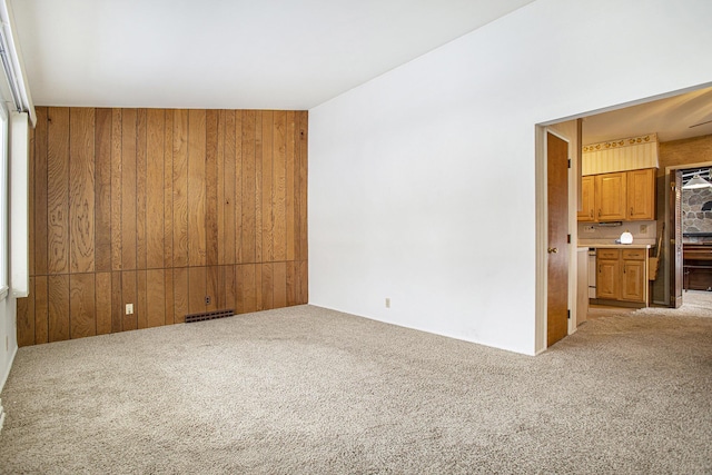 empty room featuring light carpet and wood walls