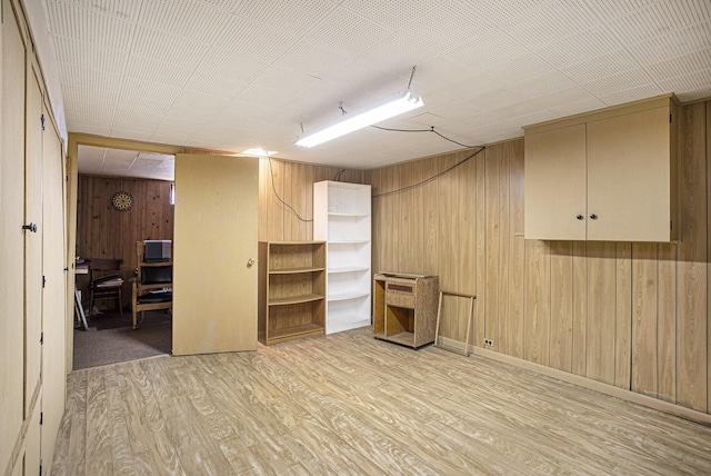 basement with light hardwood / wood-style floors and wood walls