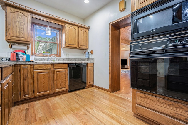 kitchen with black appliances, light wood-type flooring, and sink