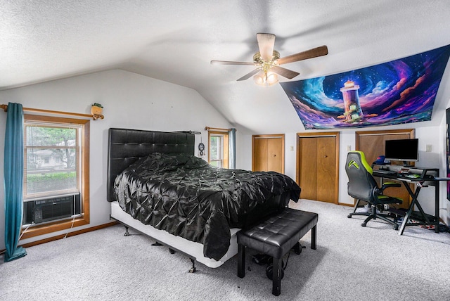 carpeted bedroom featuring ceiling fan, cooling unit, vaulted ceiling, a textured ceiling, and two closets