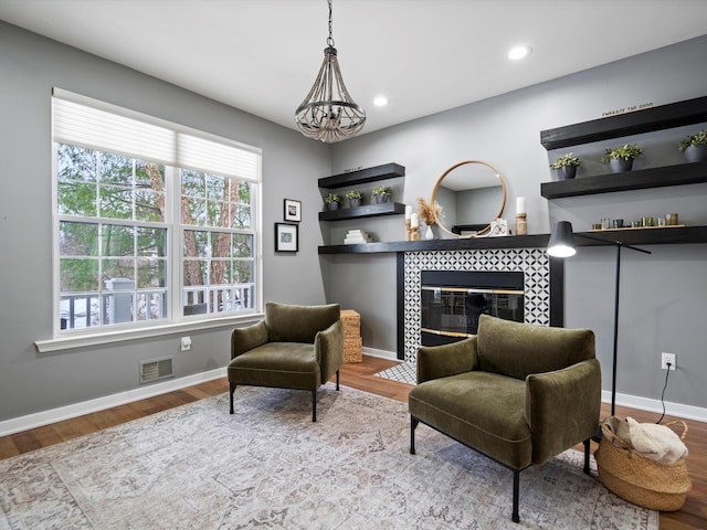 sitting room with a fireplace, a notable chandelier, and light hardwood / wood-style flooring