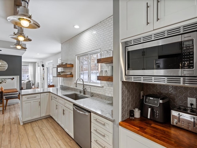 kitchen with stainless steel appliances, tasteful backsplash, light wood-type flooring, white cabinets, and sink