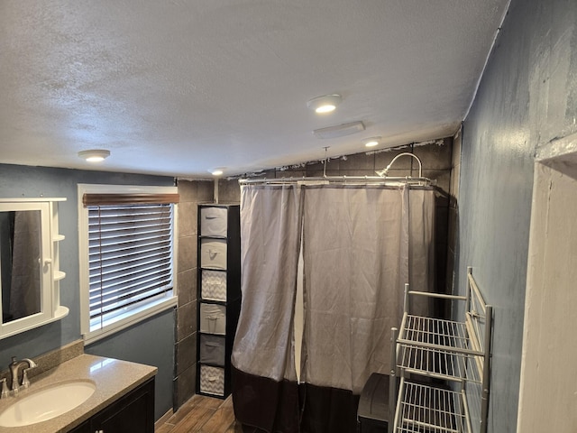 bathroom with a shower with curtain, vanity, a textured ceiling, vaulted ceiling, and wood-type flooring