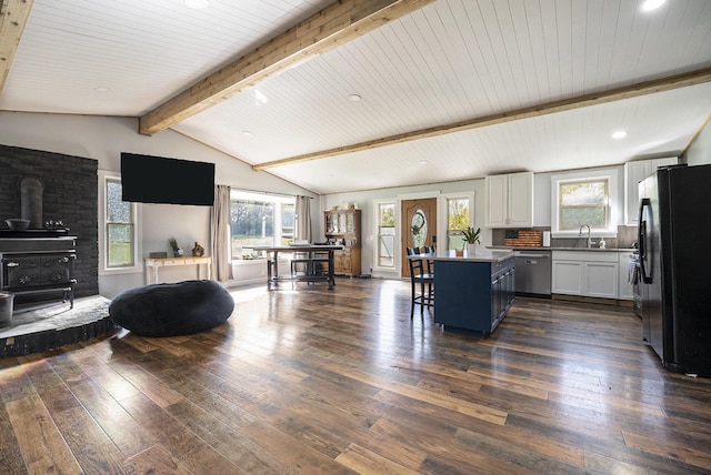 kitchen with white cabinets, a center island, a wood stove, black fridge, and wood ceiling