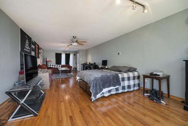 bedroom featuring rail lighting, ceiling fan, and wood-type flooring