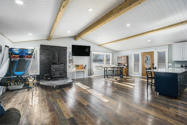 interior space featuring dark hardwood / wood-style flooring, wooden ceiling, lofted ceiling with beams, and a wood stove