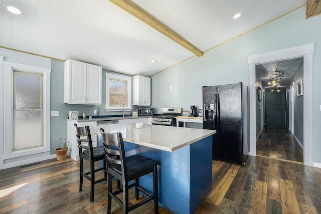 kitchen featuring white cabinets, dark hardwood / wood-style floors, a kitchen island, lofted ceiling with beams, and black appliances