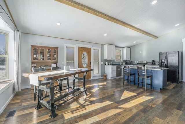 dining room with dark hardwood / wood-style flooring, lofted ceiling with beams, and plenty of natural light