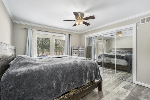 bedroom with hardwood / wood-style flooring, ceiling fan, crown molding, and a closet