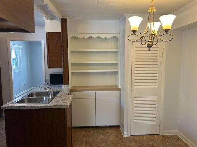 kitchen featuring decorative light fixtures, kitchen peninsula, a chandelier, and sink