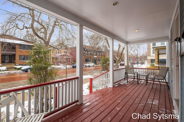 snow covered deck featuring covered porch