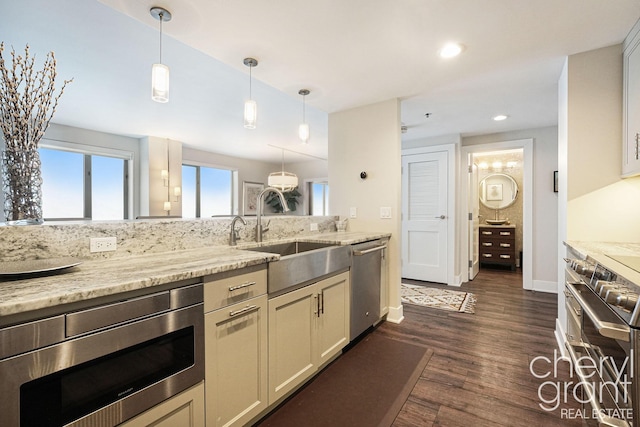 kitchen featuring light stone countertops, sink, hanging light fixtures, dark hardwood / wood-style flooring, and appliances with stainless steel finishes