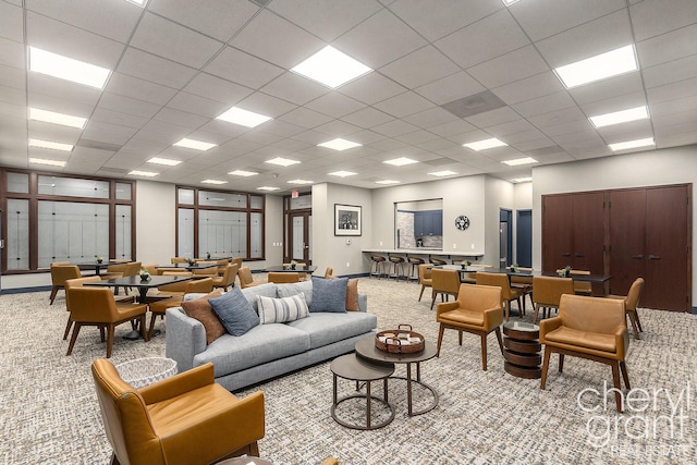 living room with a drop ceiling and light colored carpet