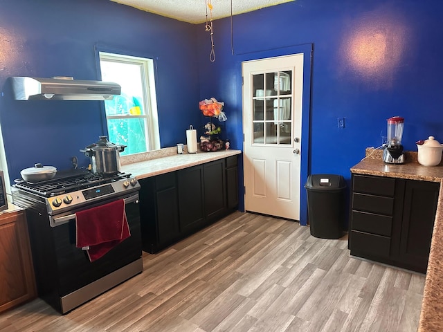 kitchen with stainless steel gas stove, light hardwood / wood-style floors, and a textured ceiling