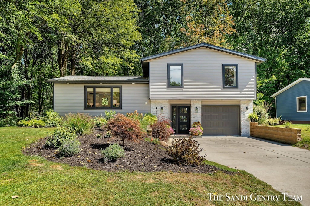 split level home featuring a garage and a front lawn