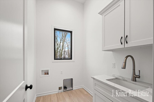 laundry area with cabinets, hookup for a washing machine, sink, and light wood-type flooring