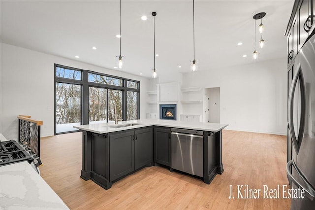 kitchen featuring light stone counters, appliances with stainless steel finishes, decorative light fixtures, and sink