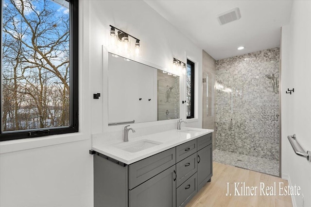 bathroom featuring vanity, wood-type flooring, and tiled shower