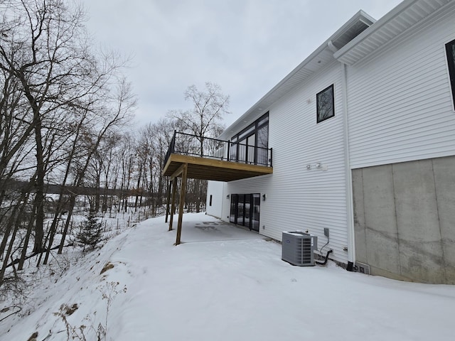 view of snowy exterior featuring central AC unit and a wooden deck