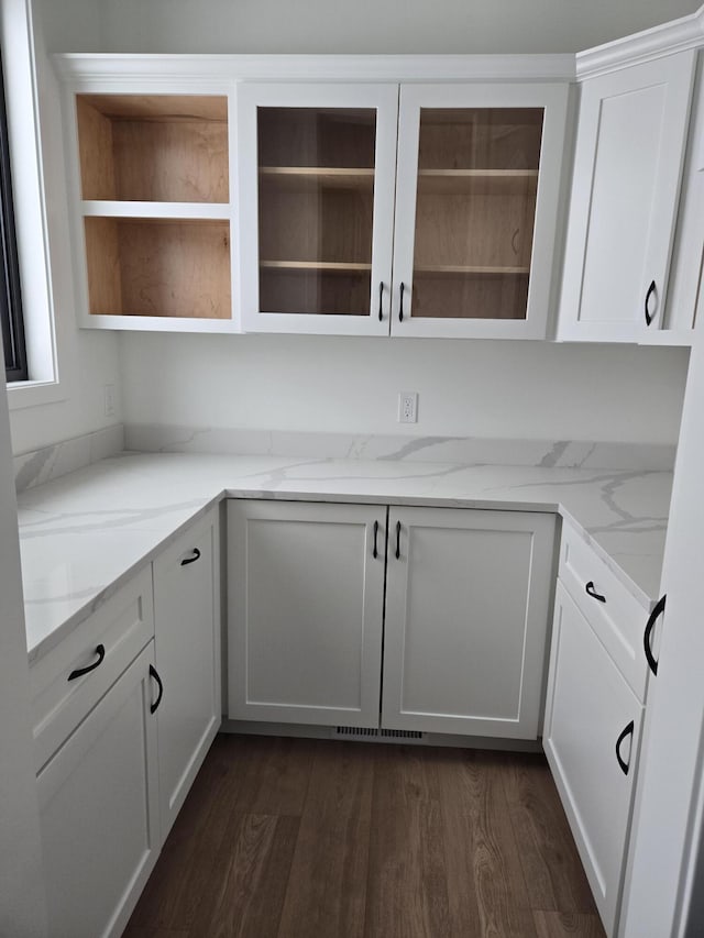 interior space featuring dark wood-type flooring, light stone countertops, and white cabinets