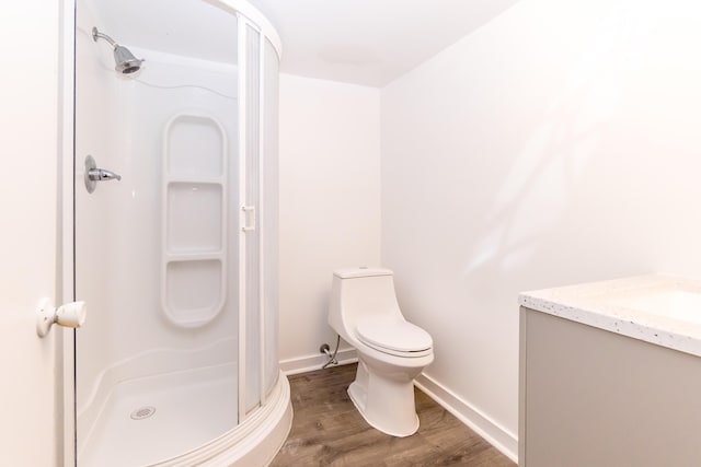 bathroom with hardwood / wood-style floors, vanity, an enclosed shower, and toilet