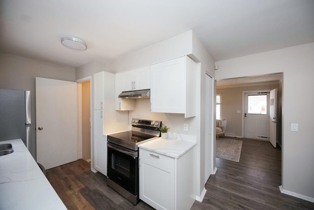 kitchen with light stone countertops, white cabinetry, stainless steel appliances, and dark wood-type flooring