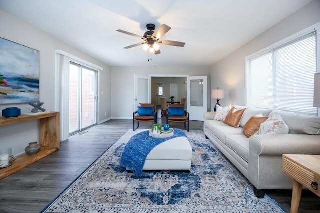 living room with dark hardwood / wood-style flooring, ceiling fan, and a healthy amount of sunlight