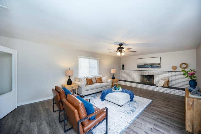 living room featuring ceiling fan, dark wood-type flooring, and a brick fireplace