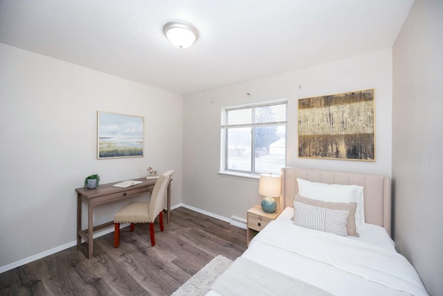 bedroom with dark hardwood / wood-style floors and a baseboard heating unit